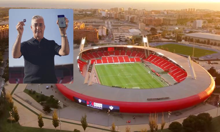 Aerial view of a large football stadium with red seating, with an inset image...