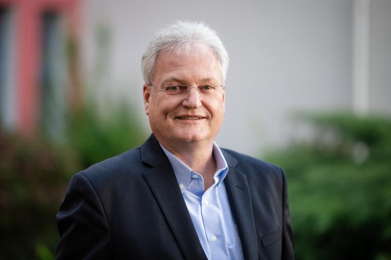Älterer Mann mit blauem Anzug und grauen Haaren