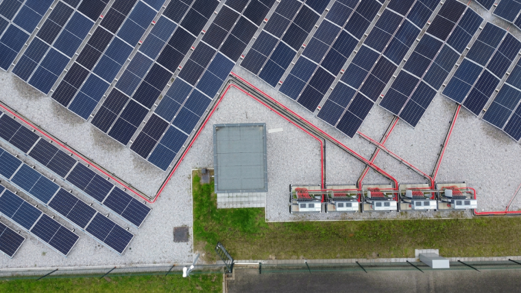 Aerial view of a solar farm with angled rows of solar panels, red cable routes,...