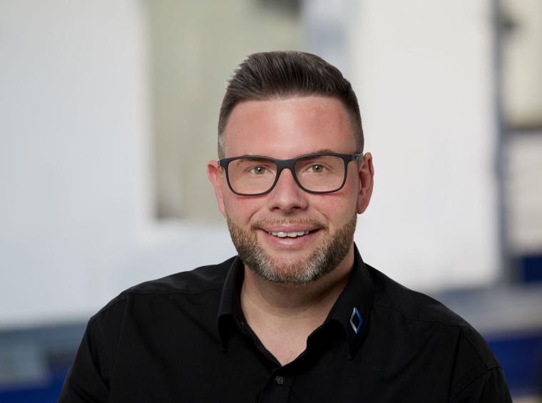 Mann mit Bart, Brille und dunklem Hemd