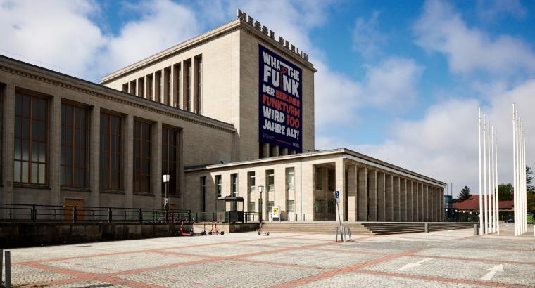 Mehrteiliges cremefarbiges Messegebäude auf größerem Platz