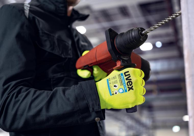Person im schwarzem Schutzanzug trägt gelbe Schutzhandschuhe und hält...