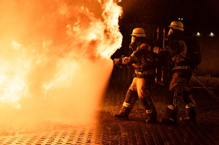 Zwei Feuerwehrmänner die eine Feuersbrunst bekämpfen