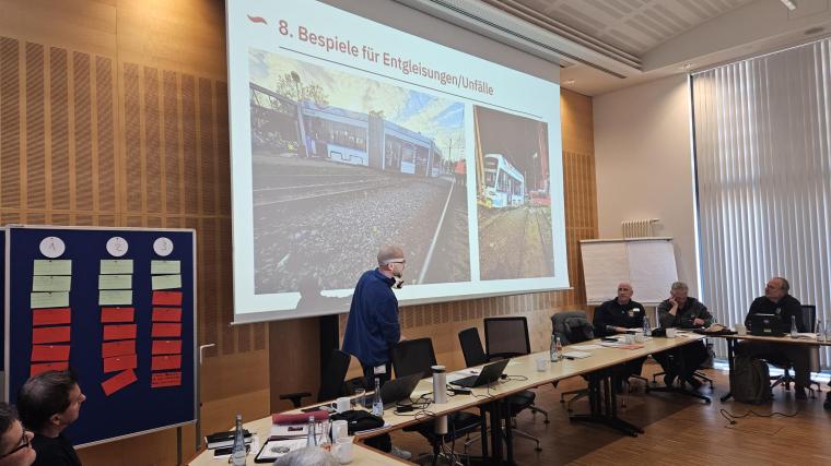 Referent vor Präsentation vor Tischreihe