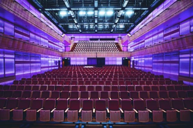 Modern concert hall auditorium with rows of red seats and purple lighting