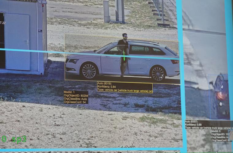 Monitorstandbild von Fahrzeug und aussteigendem Fahrer mit gelb markierten...