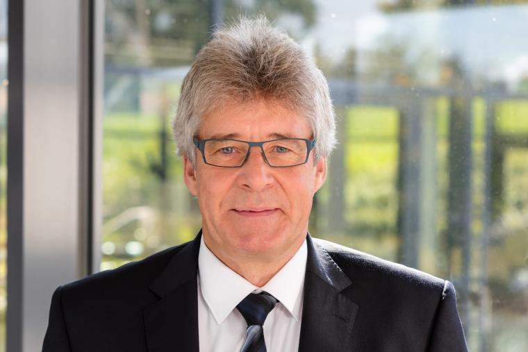 Mann mit grauen Haaren, Brille und Anzug