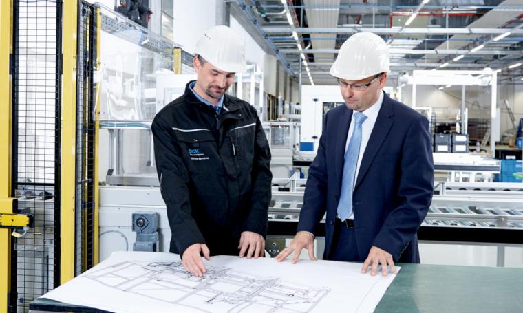 Zwei Personen in einer industriellen Anlage schauen auf einen Lageplan