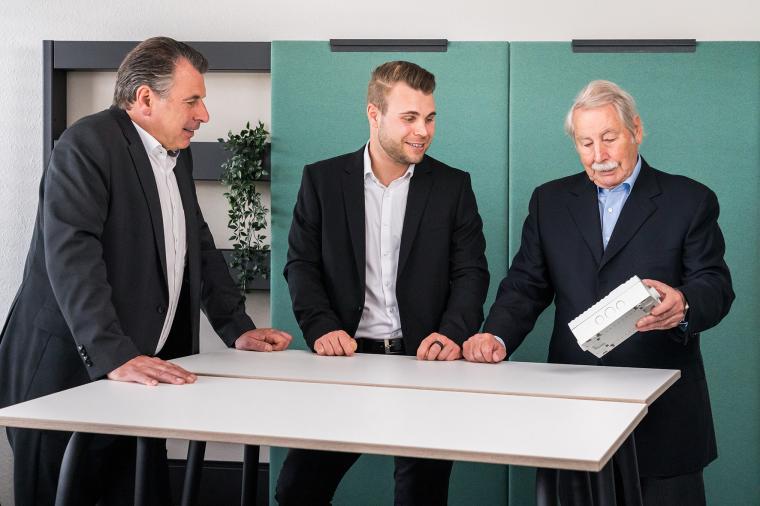 Drei Männer an einem Tisch stehend