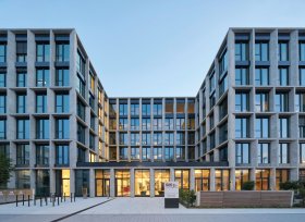 Modernes sechsstöckiges Bürogebäude mit Glasfassade und zentralem Eingang; davor gepflasterter Platz mit GASAG-Schild