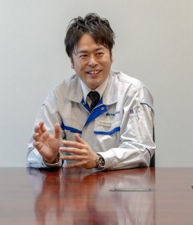 Eine Person in einem weiß-blauen Arbeitsanzug mit dem aufgestickten Namenszug „Betsuwa