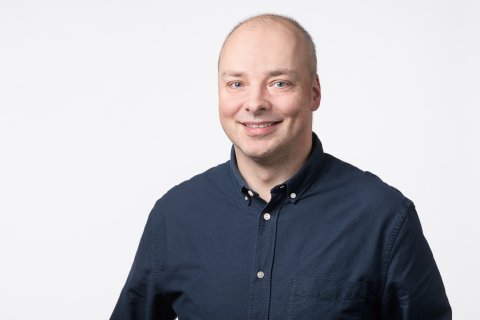 Brustbild eines jüngeren Mannes mit blauem Button-Down-Hemd