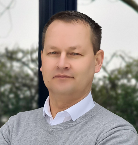 Mann mit grauem Pullover und weißem Hemd