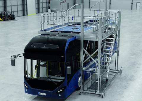Arbeitsplattform umschließt einen Bus in einer Werkhalle und ermöglicht sicheren Zugang für Wartungsarbeiten am Fahrzeugdach