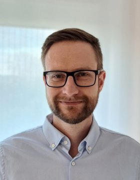 Lächelnder jüngerer Mann mit Bart und Brille