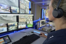 Frau mit Headset vor Monitoren