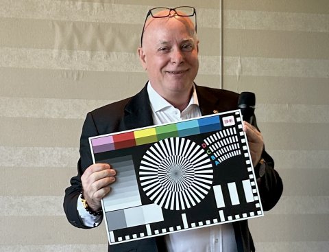 Mittelalter Mann mit Glatze und Brille auf der Stirn hält ein Testbild-Schild vor sich