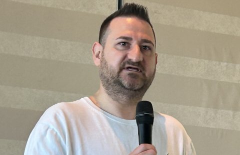 Mann mit Dreitagebart und weißem Shirt mit Mikro