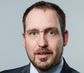 Mann mit kurzen Haaren, grauem Anzug und gestreifter Krawatte