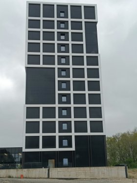 Graues Hochhaus mit weißem, durchbrochenem Schachbrettmuster