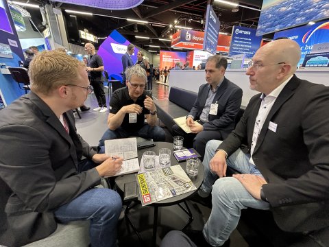 vier Personen an einem Tisch auf einem Messestand